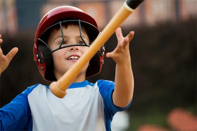 Child wearing a baseball helmet holding a bat