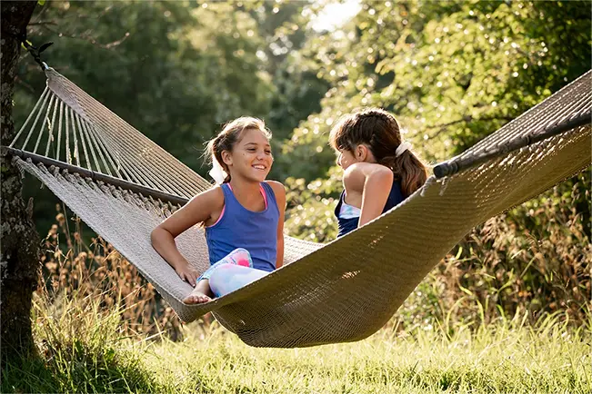 Two children relaxing in hammocks outdoors