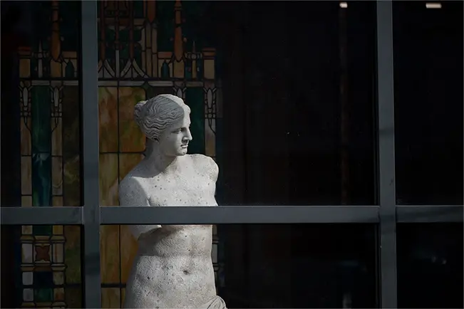 Statue framed by a window with stained glass behind it