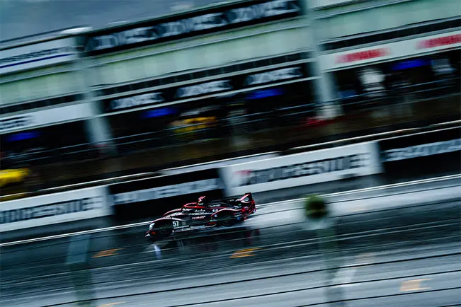 Race car speeding along a wet track with motion blur