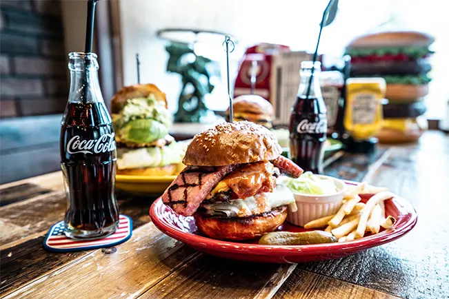 Burger and fries served on a red plate with Coca-Cola bottles