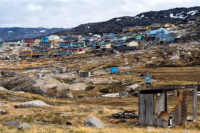 Colorful coastal settlement surrounded by rocky hills and snow