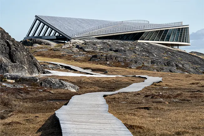 Modern building on a rocky hillside with a winding wooden walkway