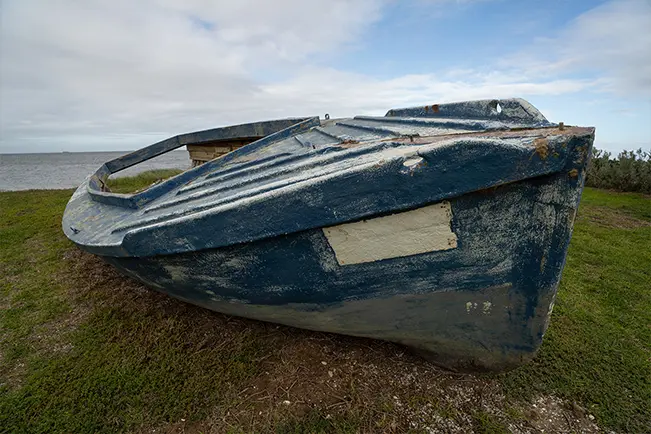 Old blue fishing boat resting on a grassy shoreline