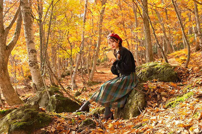 Woman sitting on a moss-covered rock in an autumn forest