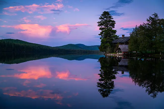 Sunset over a calm lake with mountain reflections at dusk