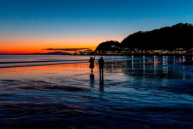 Person standing in shallow ocean water at sunset